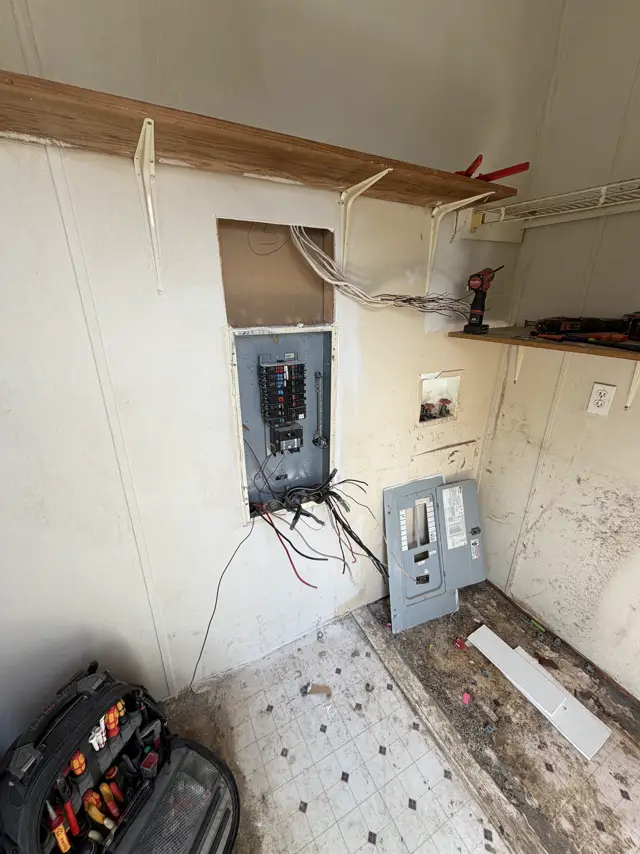 Old electrical panel opened up during a panel swap, with the old cover set aside
